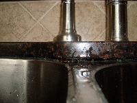 Gap between center of sink and granite, near faucet